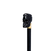 Bastón elegante con mango de calavera negra esculpida y detalles en oro
